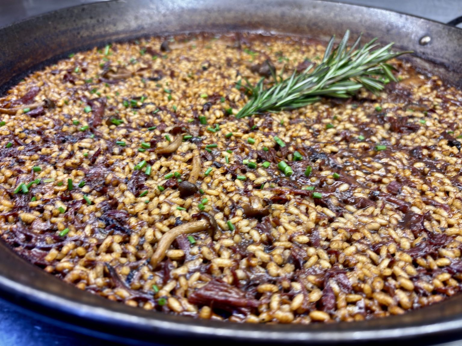 Arroz de morcillo de buey en paellera, con romero y cebollino recién añadidos