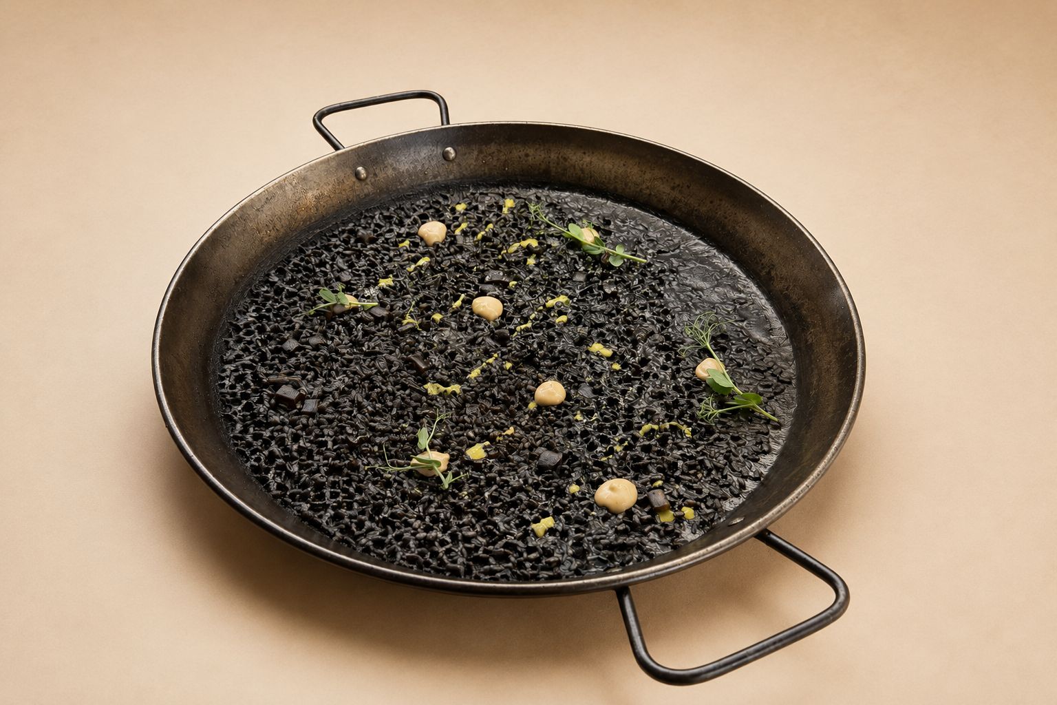 Arroz negro con calamar sahariano y puntos de alioli de ajo negro en paellera